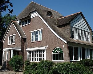 Zijaanzicht van Villa Vacuna, charmant vakantiehuis in Domburg, Walcheren met rieten dak.