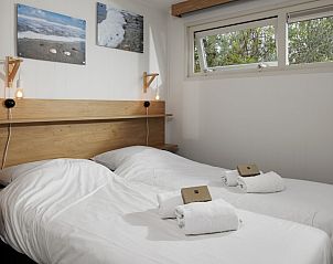 Gezellige slaapkamer in SCR chalet Domburg, Walcheren, Zeeland met twee bedden en uitzicht op groene natuur.