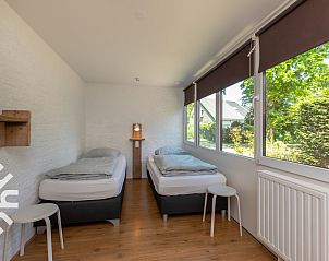 Houten poort van vakantiehuis ZE1422 in Zoutelande, Walcheren, met bloemen en groene haag.