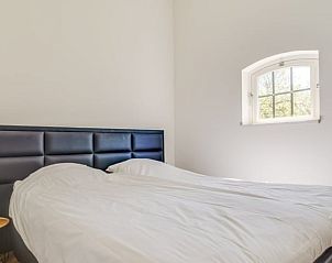 Sfeervolle slaapkamer in Vakantiehuisje in Veere, Walcheren, Zeeland met comfortabel bed en rustgevend uitzicht door een charmant raam.