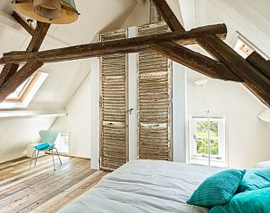 Sfeervolle slaapkamer in Mariekerke vakantiehuis, Meliskerke, Walcheren, met houten balken en rustiek interieur.