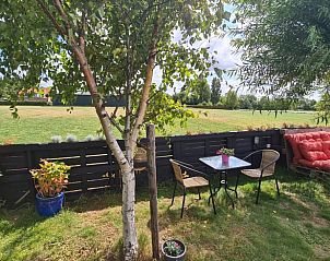 Buiten zitplek met tafel in de tuin van Vakantiehuis in Middelburg, Walcheren, Zeeland met uitzicht op natuur.