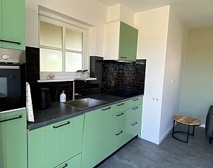 Moderne keuken in Huisje in Middelburg, een vakantiehuis in Walcheren, Zeeland, met groene kasten en een stijlvol zwart aanrecht.