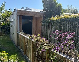 Vakantiehuis in Biggekerke met charmante houten buitenkant, omgeven door bloeiende tuin in Walcheren, Zeeland.
