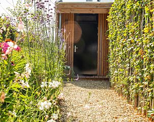 Ingang van Vakantiehuis in Biggekerke omgeven door bloeiende tuin, gelegen op Walcheren in Zeeland, biedt rust en natuur.
