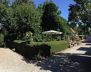 Veranda van VZ037 Vakantiehuisje Koudekerke-Dishoek omgeven door groen in Walcheren, Zeeland.