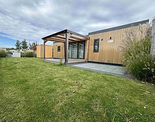 Chalet 165 in Koudekerke-Dishoek, Walcheren, Zeeland, met een uitnodigende veranda en groene omgeving voor een ontspannen vakantie.