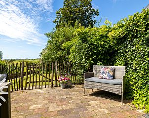 Sonniger Innenhof des Ferienhauses ZE833, Buttinge, Walcheren, mit Sitzgelegenheiten und Blumen.