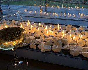 Gezellige sfeer met open haard en wijnglas in chalet Vitamin Sea, Breskens, Zeeuws-Vlaanderen, Zeeland.