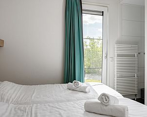 Helles Schlafzimmer der Lodge 4B in Breskens, Zeeland, mit Zugang zu einem eigenen Bad und Gartenblick.