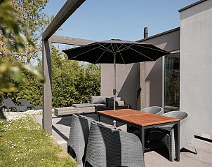 Gerumige Terrasse der Lodge 4B in Breskens, Zeeland, mit Sitzgelegenheiten und Sonnenschirm fr ein entspanntes Leben im Freien.