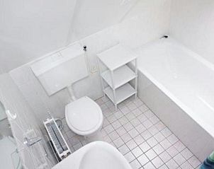 VZ967 Ferienhaus in Breskens, helles Badezimmer mit Badewanne und Toilette in Zeeuws-Vlaanderen, Zeeland.