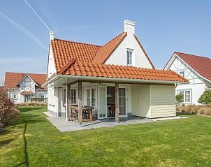 Watervilla 8B Luxe in Cadzand-bad, Zeeuws-Vlaanderen, a charming vacation home with red roof tiles and an inviting terrace in the green garden.