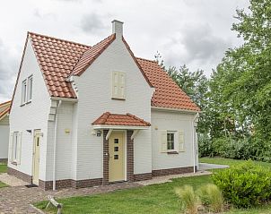 Villa 8A Luxe in Cadzand-bad, Zeeland, a charming vacation home surrounded by greenery and rustic architecture.