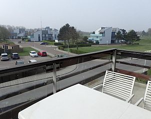 View from the balcony of VZ922 Holiday apartment in Cadzand, overlooking modern architecture and green surroundings in Zeeland.