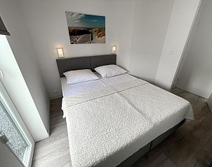 Sfeervolle slaapkamer in Vakantiehuis Waterresort Oosterschelde huisnr. 83 in Wemeldinge, met comfortabel bed en decoratief kunstwerk.