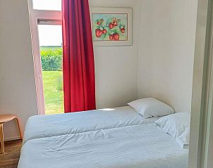 Tweede slaapkamer in Vakantiehuis Waterresort Oosterschelde huisnr. 51, met helder daglicht en uitzicht op groene velden.