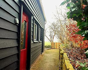 Sfeervolle ingang van Vakantiehuisje in Wolphaartsdijk, Zuid-Beveland, met rode deur.