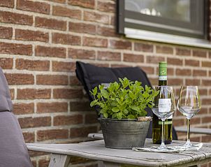 Ontspannende zithoek buiten bij Vakantiehuis Haus Anni, Hansweert, Zuid-Beveland, met wijn en glazen.