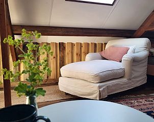 Gezellige zithoek in het Vakantiehuisje in Rilland, Zuid-Beveland, met comfortabele fauteuil en houten interieur voor een ontspannen verblijf.