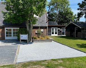 Vooraanzicht van Vakantiehuisje in Streefkerk met grindpad en groene omgeving.