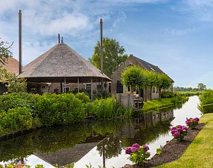 Prachtig uitzicht op het Vakantiehuis in Stolwijk met rieten dak en gracht, gelegen in de Alblasserwaard, Zuid-Holland.