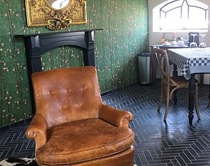 Stijlvolle woonkamer in Vakantiehuis in Stolwijk met leren stoel en decoratieve haard, Alblasserwaard, Zuid-Holland.