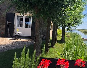 Buitenterras bij Vakantiehuis in Stolwijk met bloemen en uitzicht op de gracht, Alblasserwaard, Zuid-Holland.