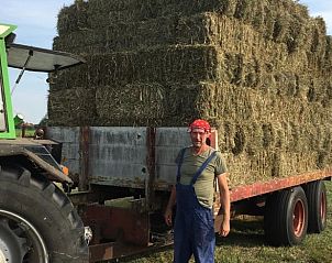Boer met hooibalen op het land bij vakantiehuis Stolwijk, Alblasserwaard, Zuid-Holland.