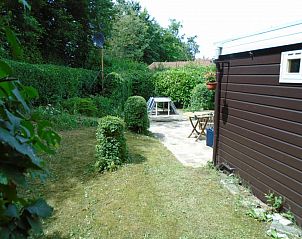 Gezellige tuin van Het Zomernest in Ouddorp met terrasstoelen en groene omgeving.
