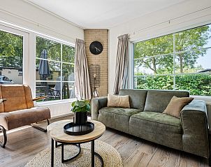 Lichte woonkamer van Bungalow Zierikzee in Ouddorp, met grote ramen en uitzicht op de tuin van Goeree-Overflakkee.