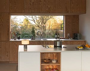 Modern kitchen in holiday home in Ouddorp, Goeree-Overflakkee, with views of nature through large window. Cozy stay in South Holland.