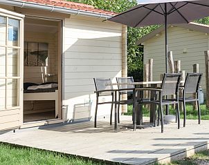 Veranda des Camping Chalet de Zeester in Ouddorp, Sdholland mit Sitzgelegenheiten unter einem Sonnenschirm zum Entspannen in der Natur.