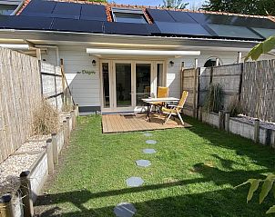 Sonnige Terrasse am Ferienhaus VZ991 in Ouddorp, Sdholland, mit bequemen Sthlen und grner Umgebung.