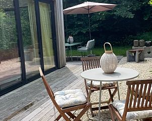 Veranda of House in Ouddorp, vacation accommodation in Ouddorp, South Holland with seating and green surroundings.