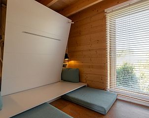 Gezellige binnenruimte van ECO Cottage in Ouddorp, Goeree-Overflakkee met houten muren en comfortabele zitplek.