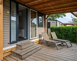 Veranda of Mobil home Grevelingen in Ouddorp, South Holland, with comfortable deck chairs for relaxation amidst nature.