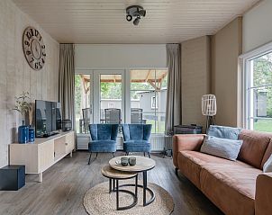 Gezellige woonkamer in Bungalow Stellendam, Ouddorp, met comfortabel interieur en uitzicht op de groene omgeving van Goeree-Overflakkee.