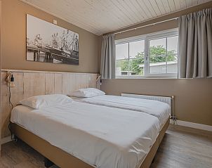 Sfeervolle slaapkamer in Bungalow Stellendam, Ouddorp, gelegen op Goeree-Overflakkee in Zuid-Holland, met comfortabele bedden en serene ambiance.