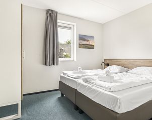 Ruime eetkamer in Strand Resort Ouddorp Duin, 24-persoons villa Sterduin in Ouddorp, Zuid-Holland, met moderne keuken en uitzicht op de tuin.