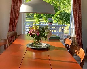 Eettafel met bloemen in Vakantiehuisje in Goedereede, uitzicht op groene tuin in Zuid-Holland.