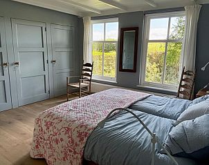 Gezellige slaapkamer in Vakantiehuisje in Goedereede met gele muren en houten meubels.