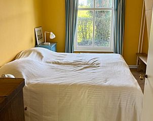 Knusse zolderkamer in Vakantiehuisje in Goedereede met houten vloer en dakraam.