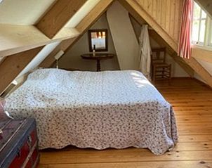 Sfeervolle slaapkamer op zolder in Vakantiehuisje in Goedereede met houten afwerking.