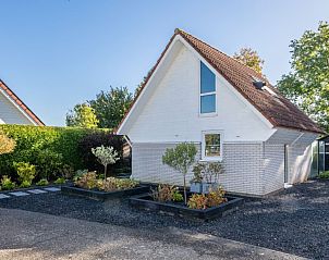 Beach House 43, een charmant vakantiehuis in Herkingen, Goeree-Overflakkee, Zuid-Holland, omgeven door groene natuur en een zonnige tuin.