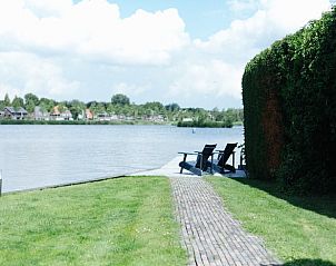 Uitzicht op het meer vanuit Vakantiehuisje in Reeuwijk, Zuid-Holland, met ligstoelen aan het water.