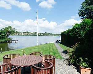 Vakantiehuisje in Reeuwijk, Groene Hart, met terras en vlag aan het water, ideaal voor buitenactiviteiten.