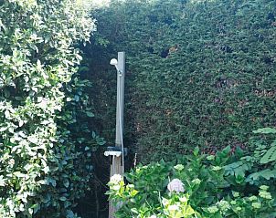 Buitendouche verscholen in de groene tuin van Vakantiehuisje in Reeuwijk, Zuid-Holland.