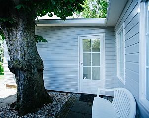 Ingang van Vakantiehuisje in Reeuwijk, Groene Hart, met bankje onder een boom voor schaduwrijke rust.