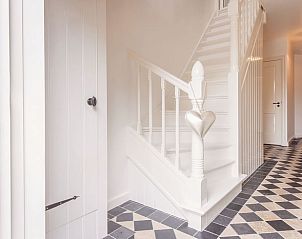 Stijlvolle entree van Vakantiehuis in Haastrecht met elegante trap en zwart-wit tegelvloer.